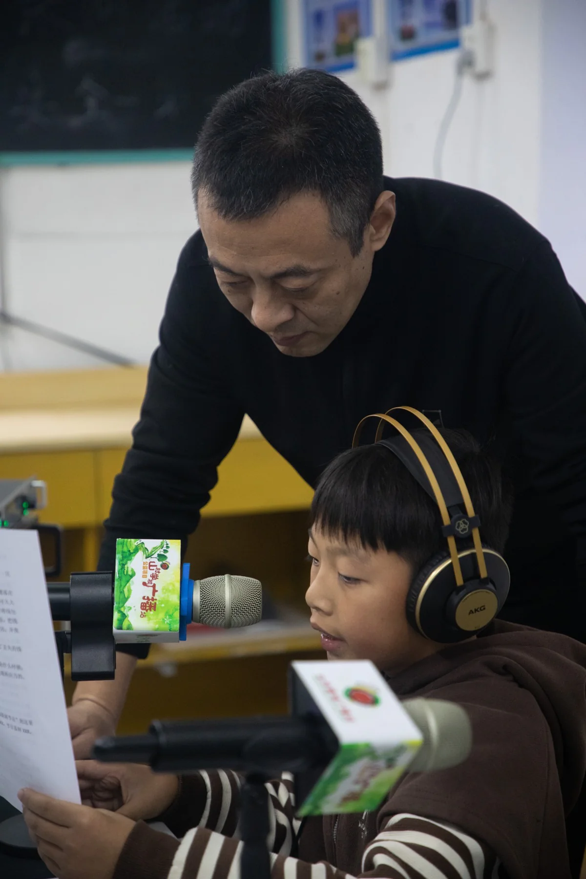 老师陪伴孩子在广播室练习播音